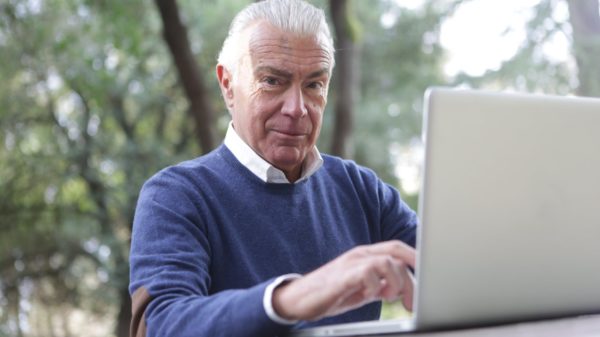 man in blue sweater typing on computer laptop