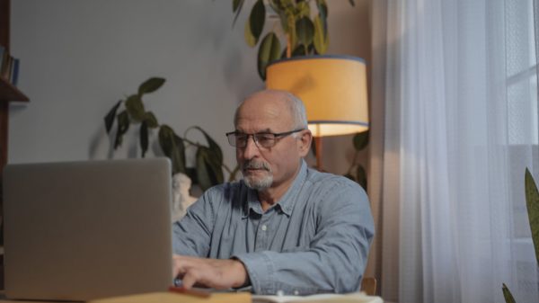 man in blue dress shirt wearing eyeglasses using macbook